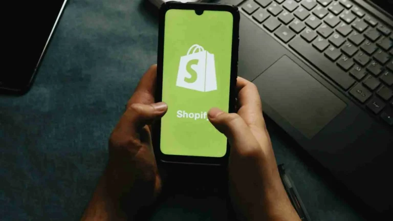 Een telefoon in de handen van iemand met een shopify logo op het beeldscherm