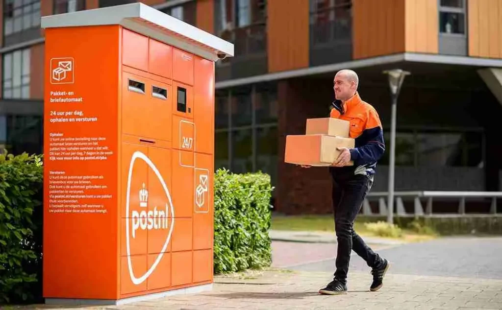 Een pakketbezorger die aan komt lopen bij een pakketautomaat van post nl